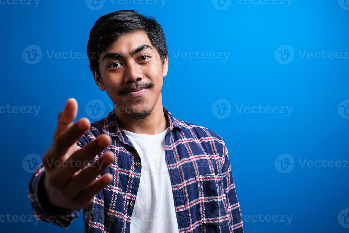 Happy asian man smiles looked at camera against blue background photo