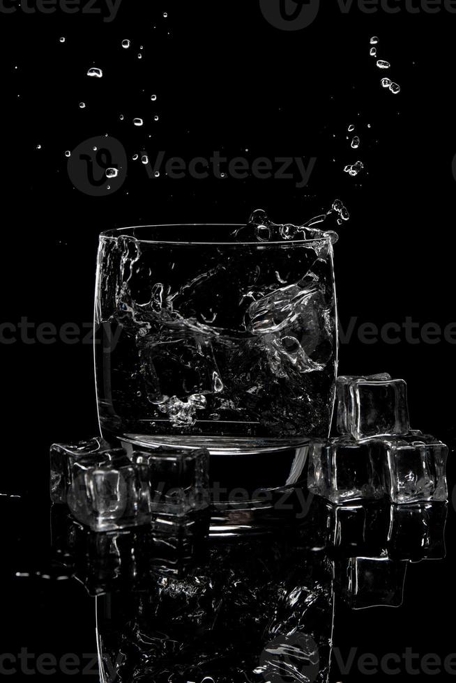 water splashing in a glass of water and ice on blackbackground photo