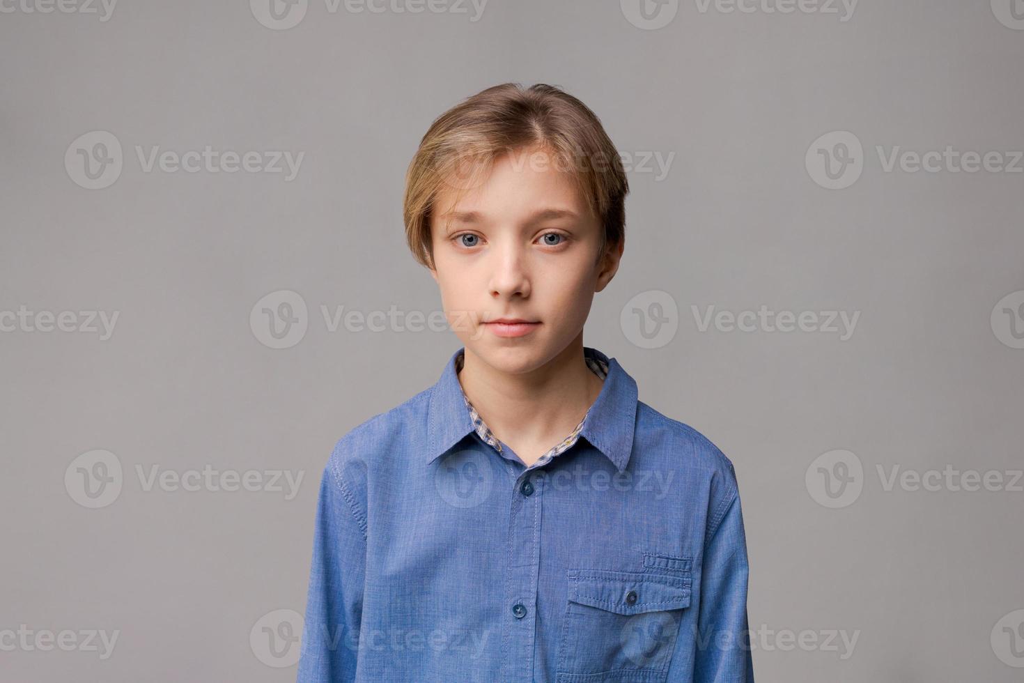 Happy millennial caucasian guy in blue shirt isolated on gray studio background photo