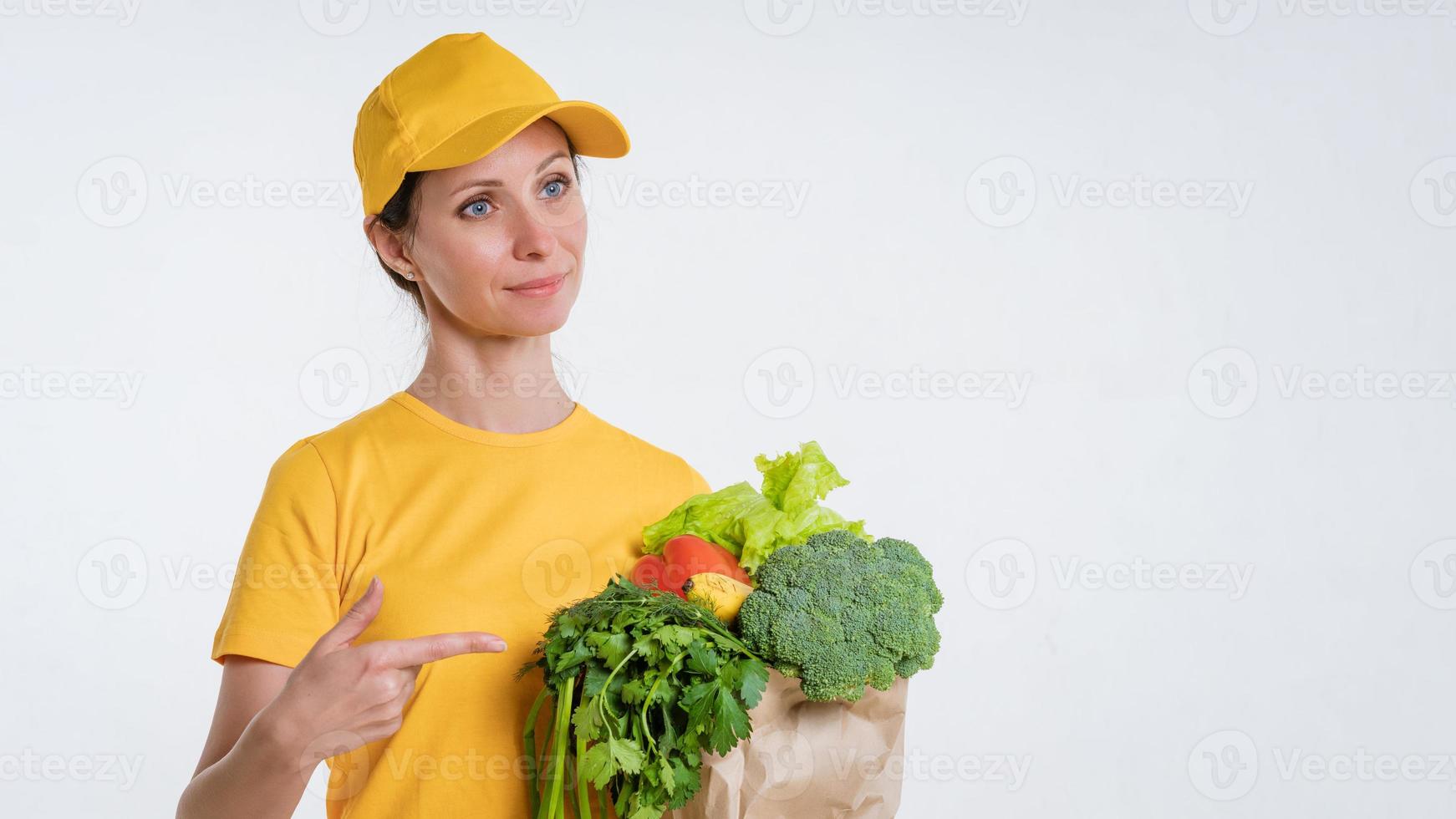 A woman in yellow clothes, delivering a package of food, on a white background photo