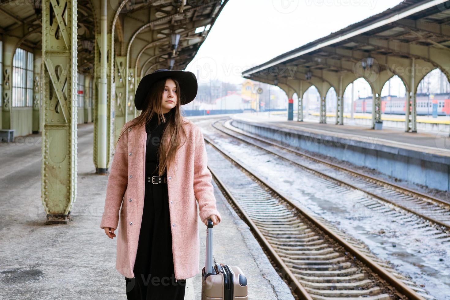 Woman traveler tourist walks with luggage at the train station. The concept of photo