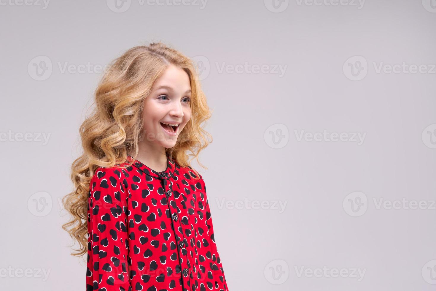 Little funny child girl 8 years old wears a red dress with long wavy hair photo