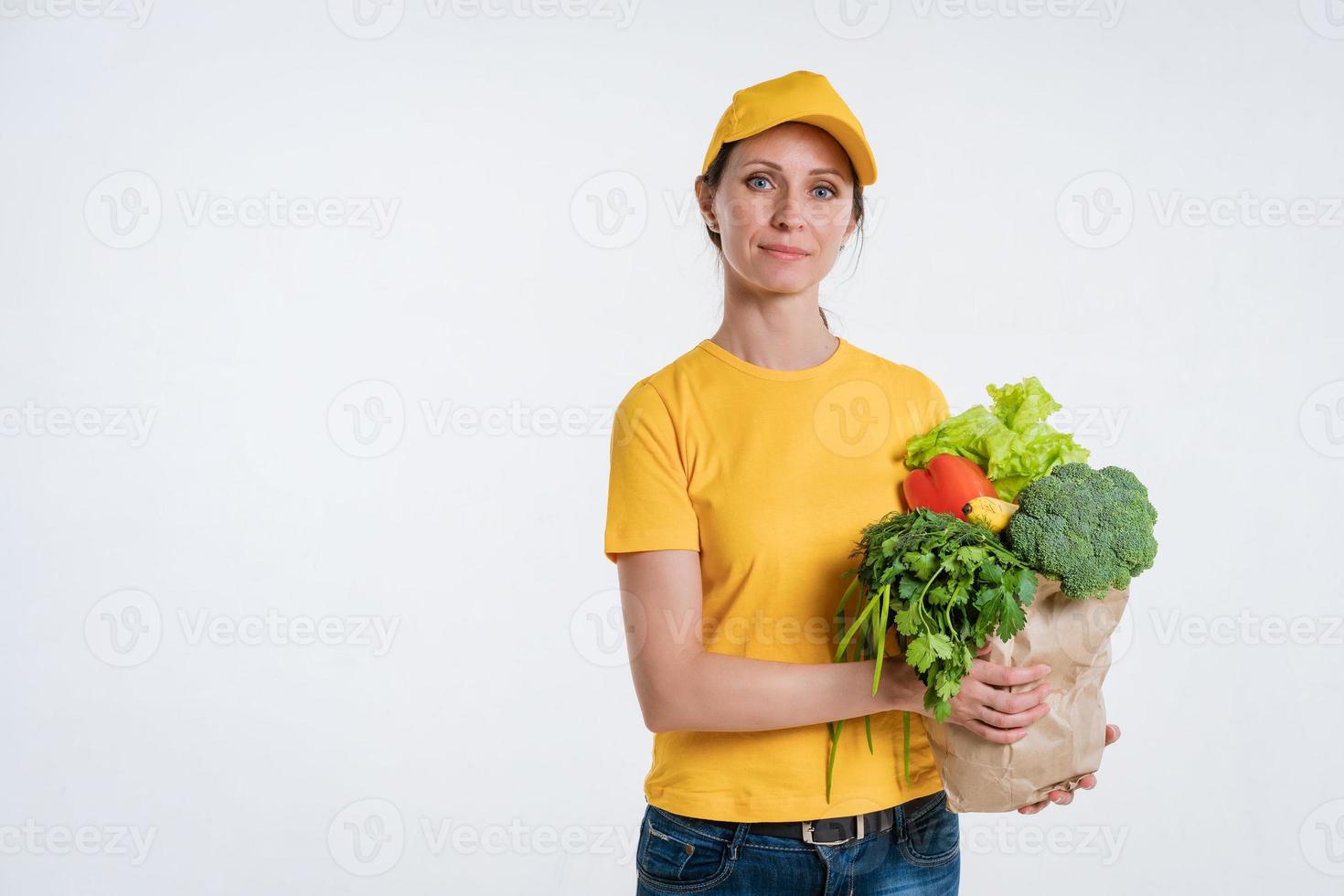 A woman in yellow clothes, delivering a package of food, on a white background photo