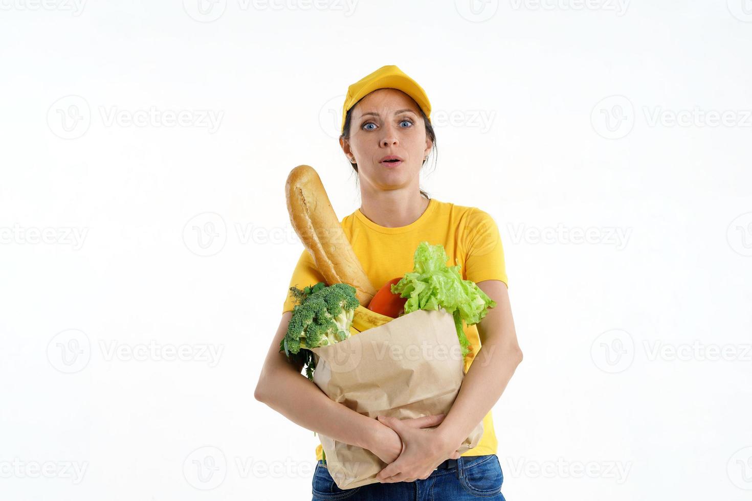 Tired delivery woman in yellow posing with grocery bag, white background photo