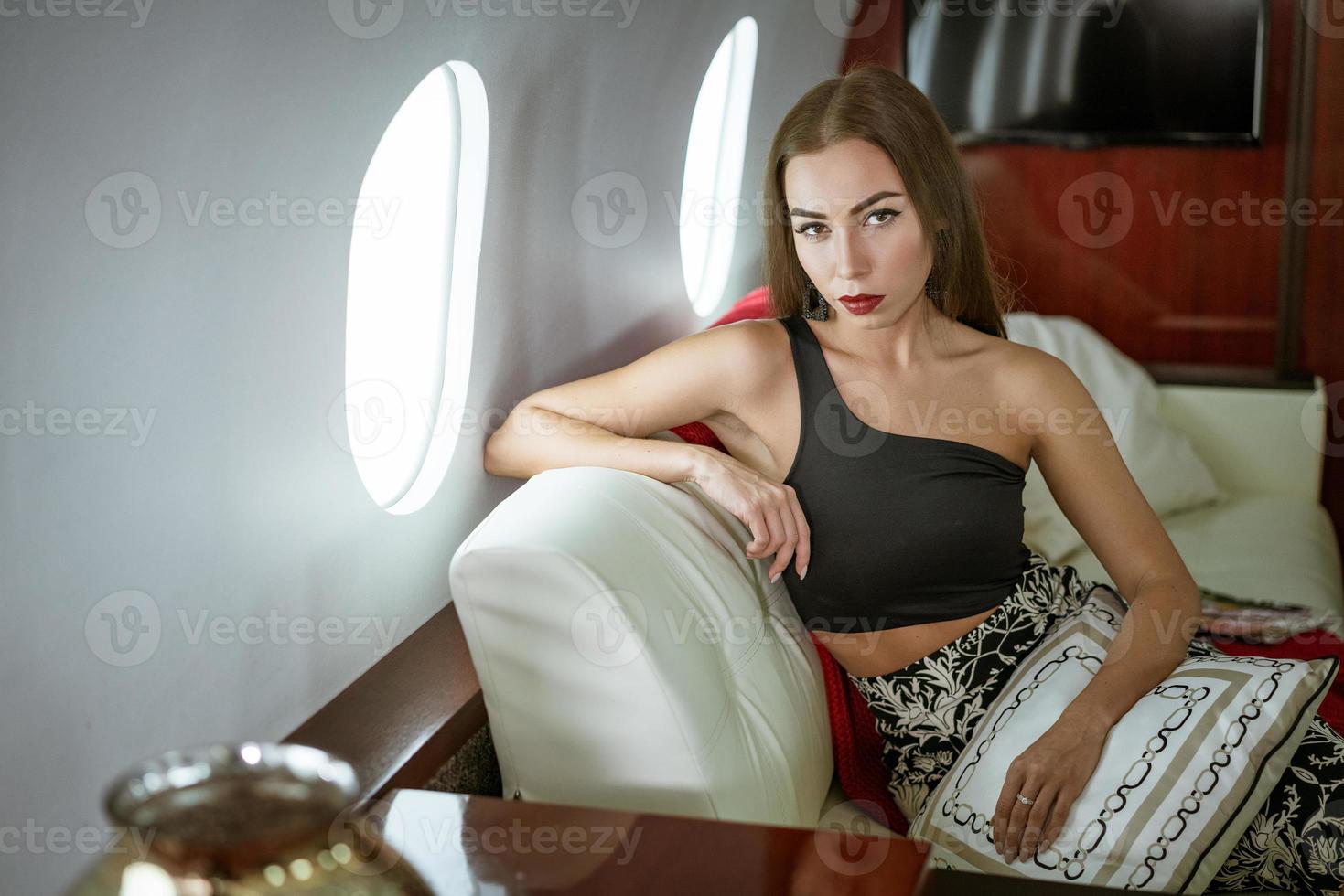hermosa mujer morena sentada en un asiento de avión privado foto