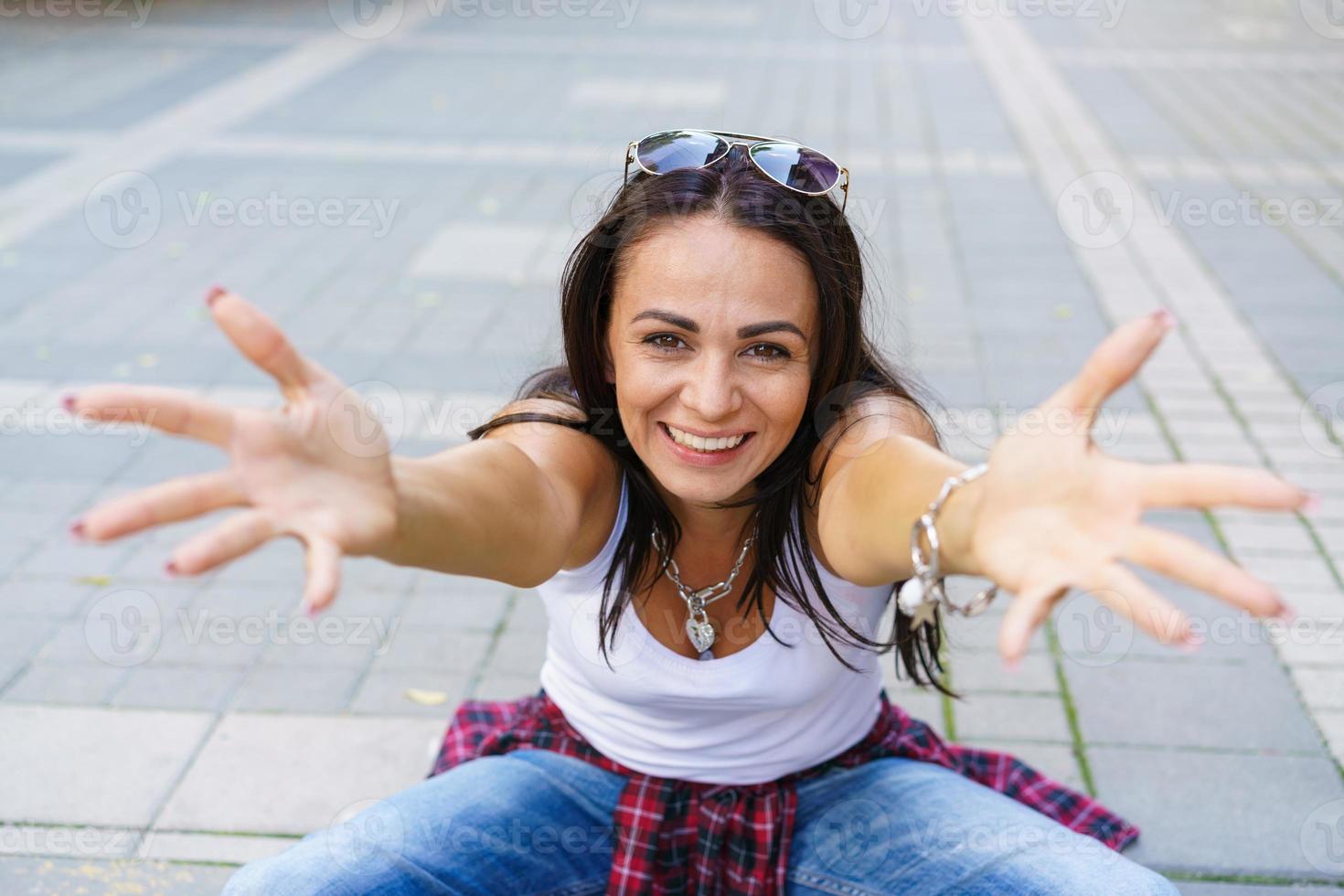 feliz moda joven mujer sentada en la acera de la calle elegante modelo femenino foto