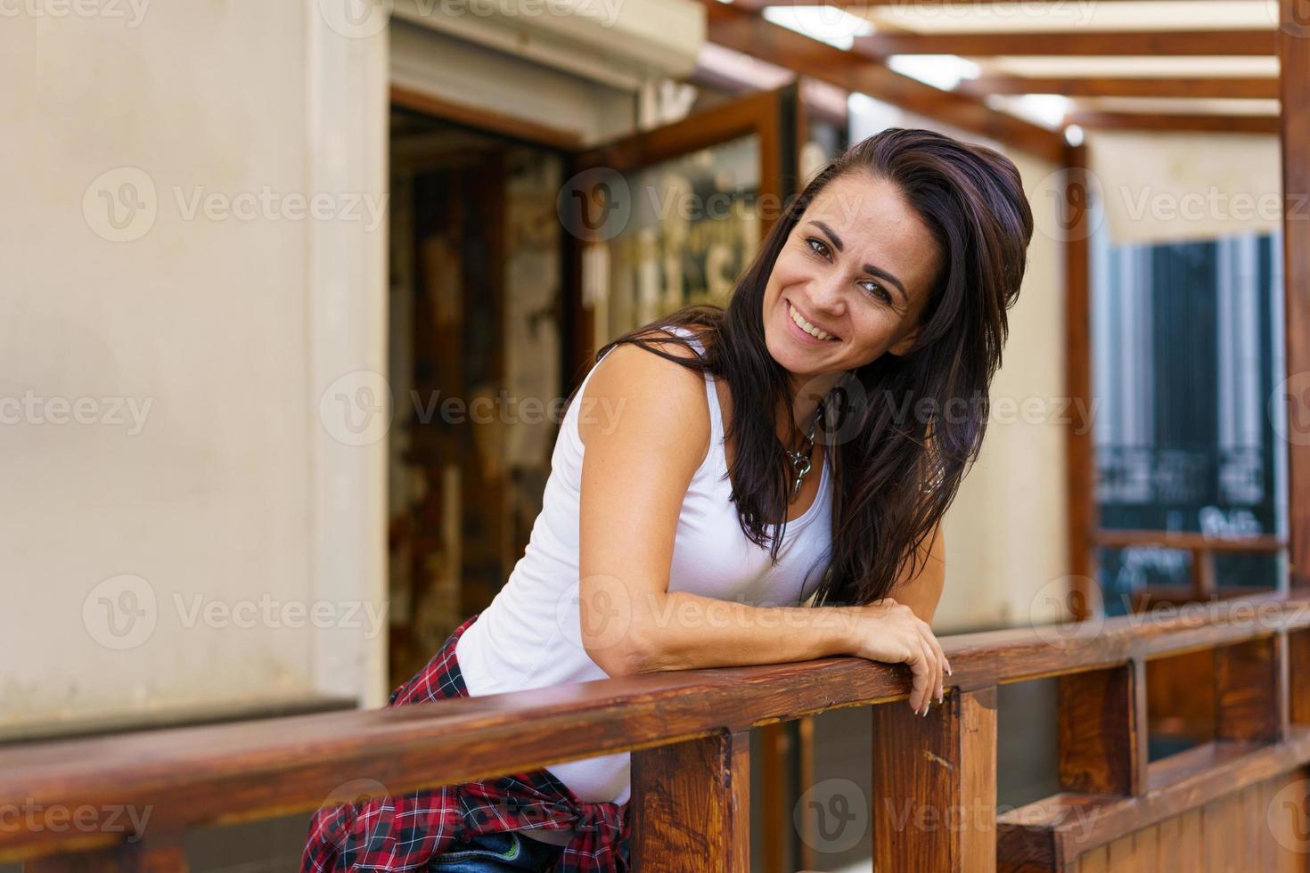 Happy smiling woman standing on veranda. Caucasian brunette girl in casual photo