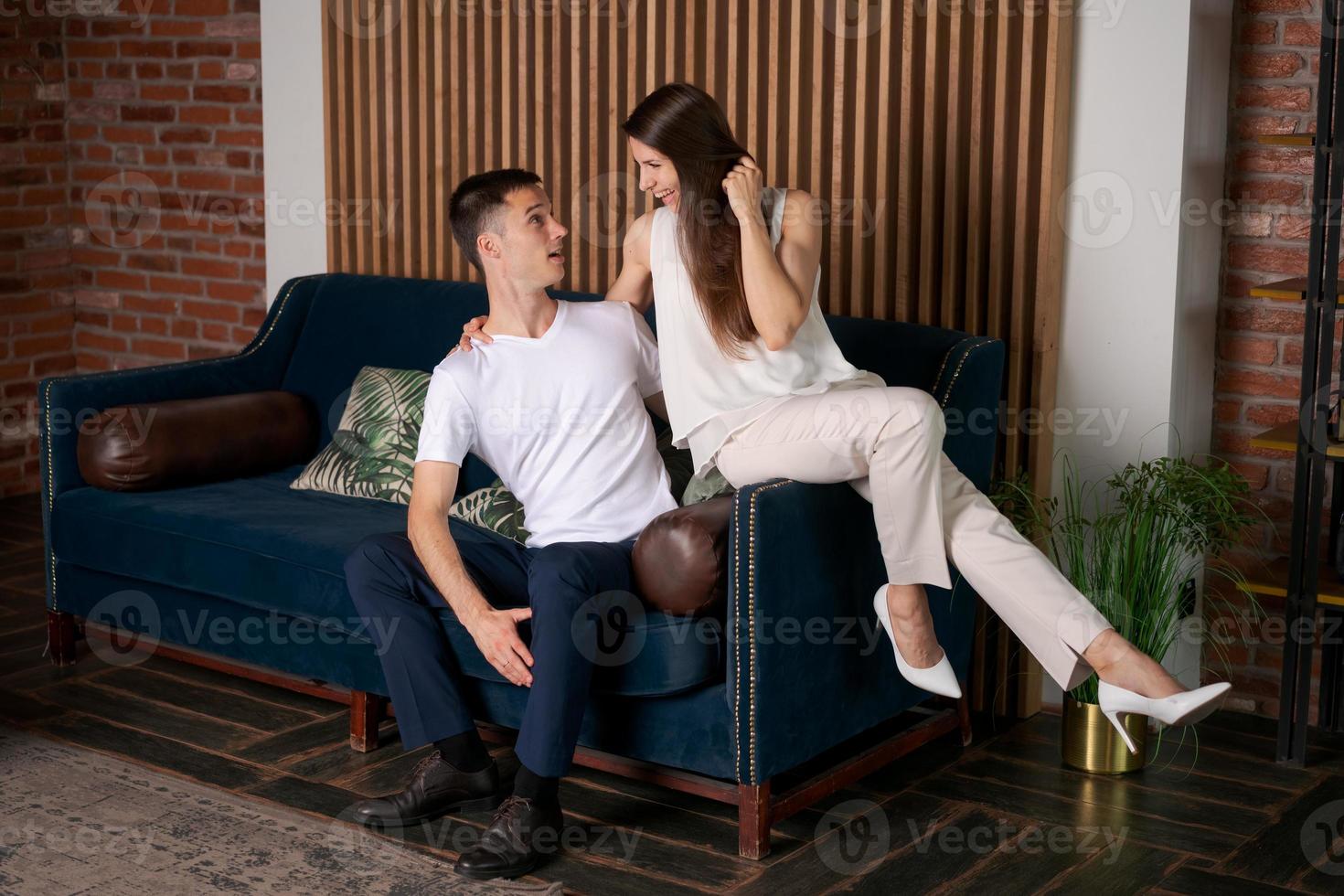 Happy married couple hugging, sitting together on cozy sofa, happy laughing photo