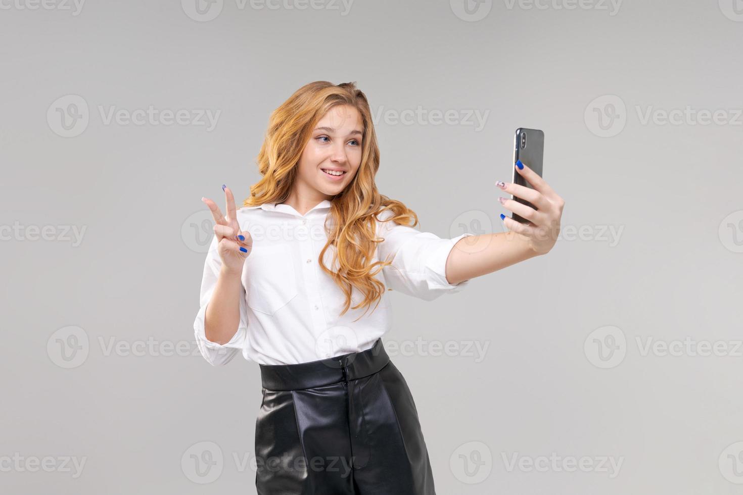 Young caucasian girl communicates by video communication using phone photo