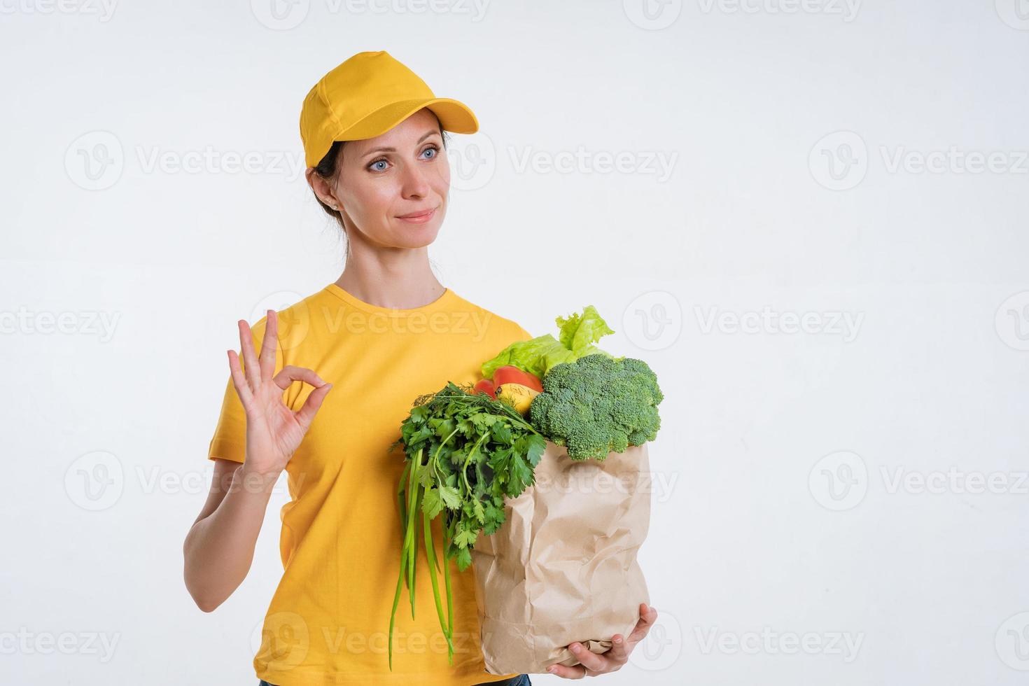 A woman in yellow clothes, delivering a package of food, on a white background photo