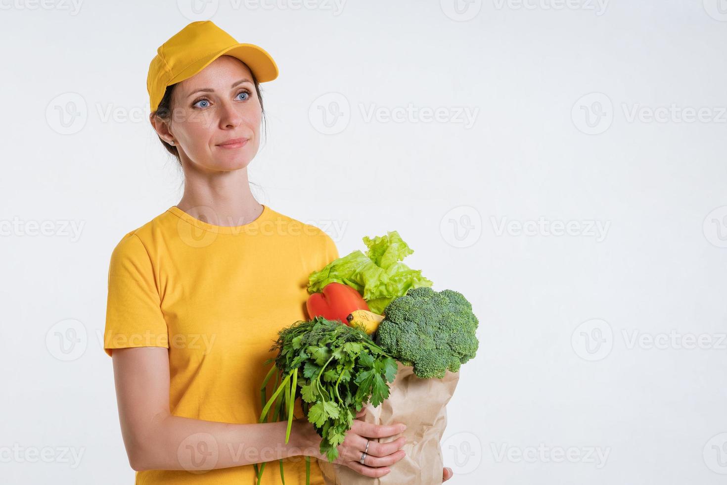 A woman in yellow clothes, delivering a package of food, on a white background photo