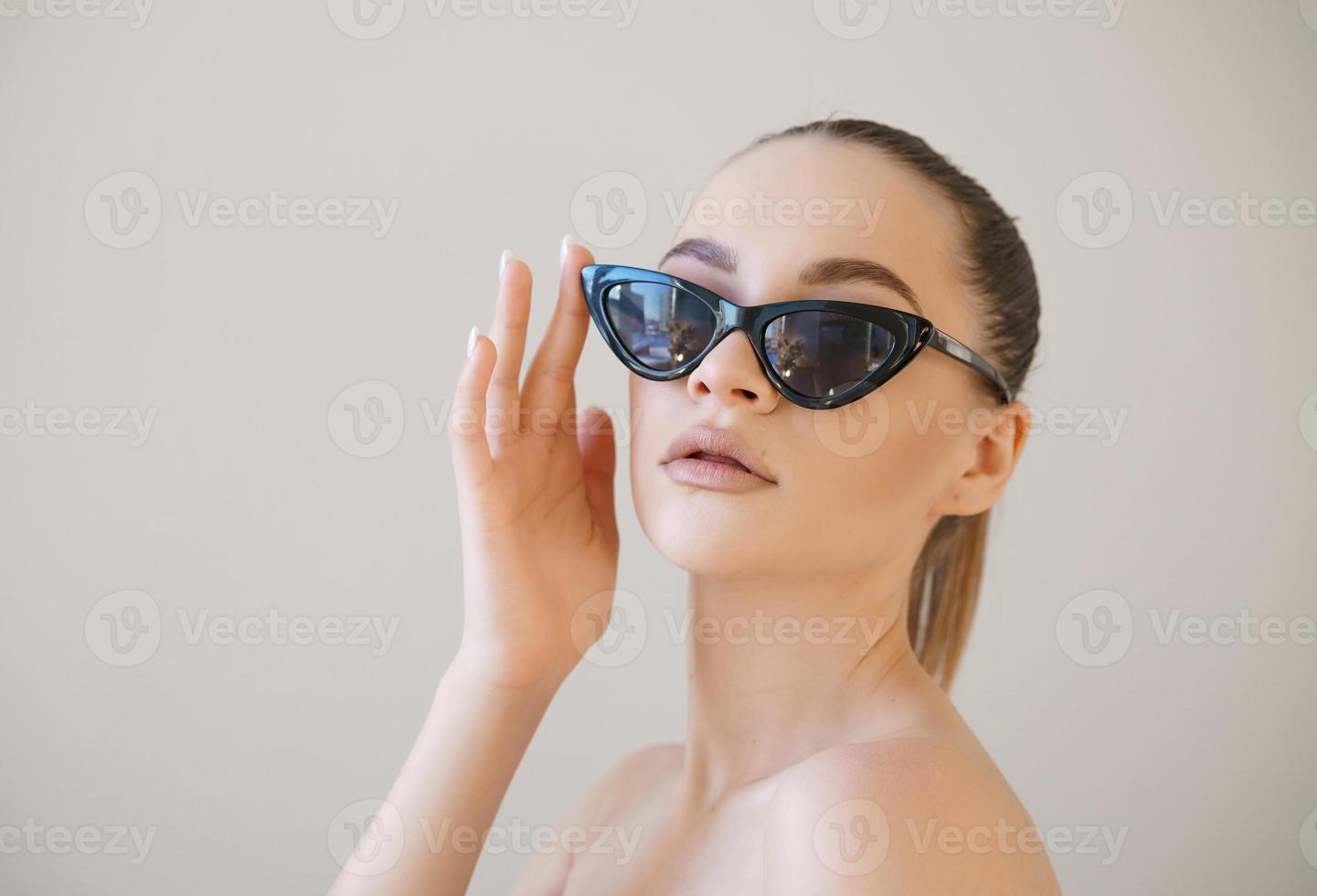 Beauty fashion model girl with brown hair wearing stylish sunglasses touches photo