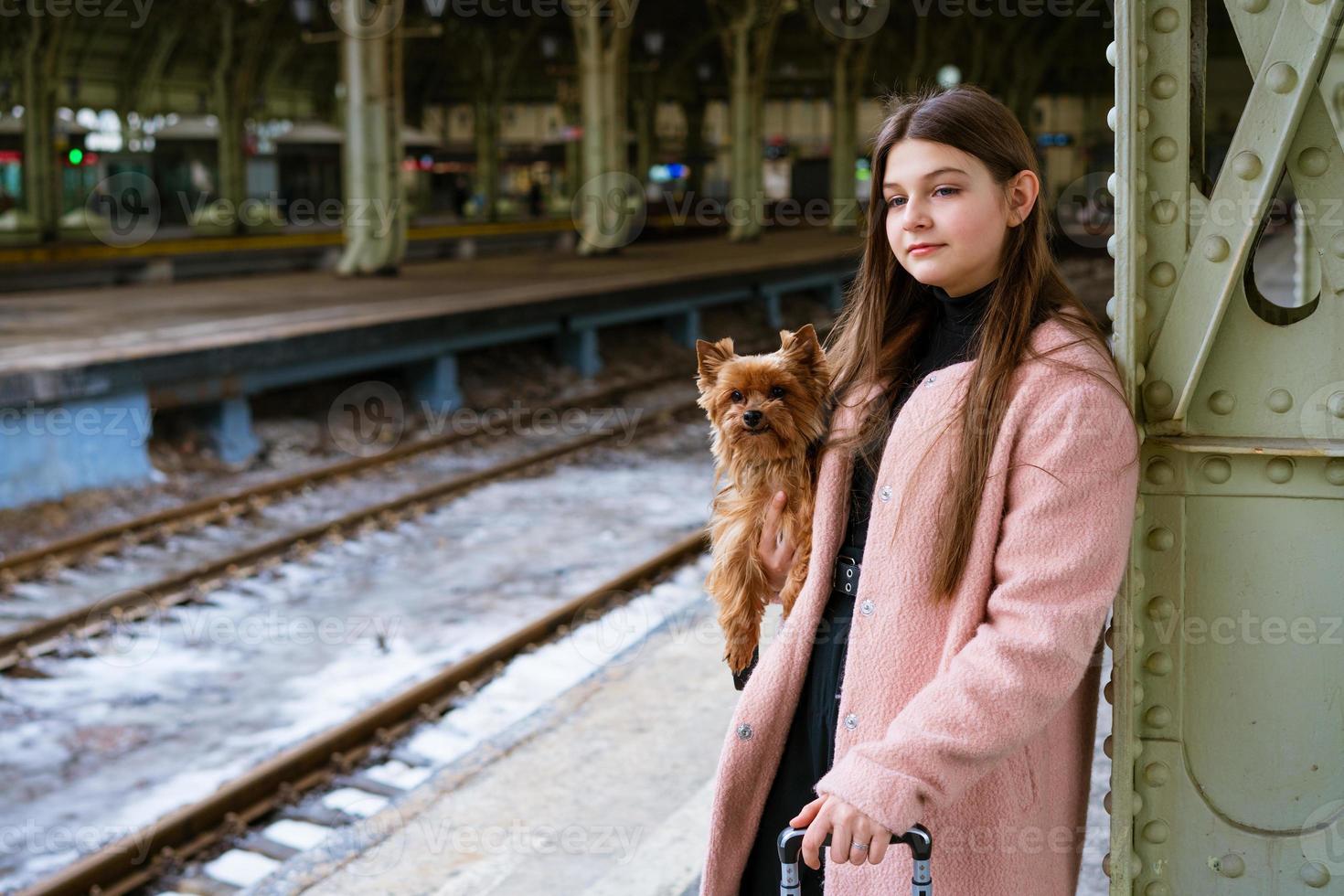joven con abrigo rosa en la estación de tren. hermosa mujer se encuentra en la plataforma foto