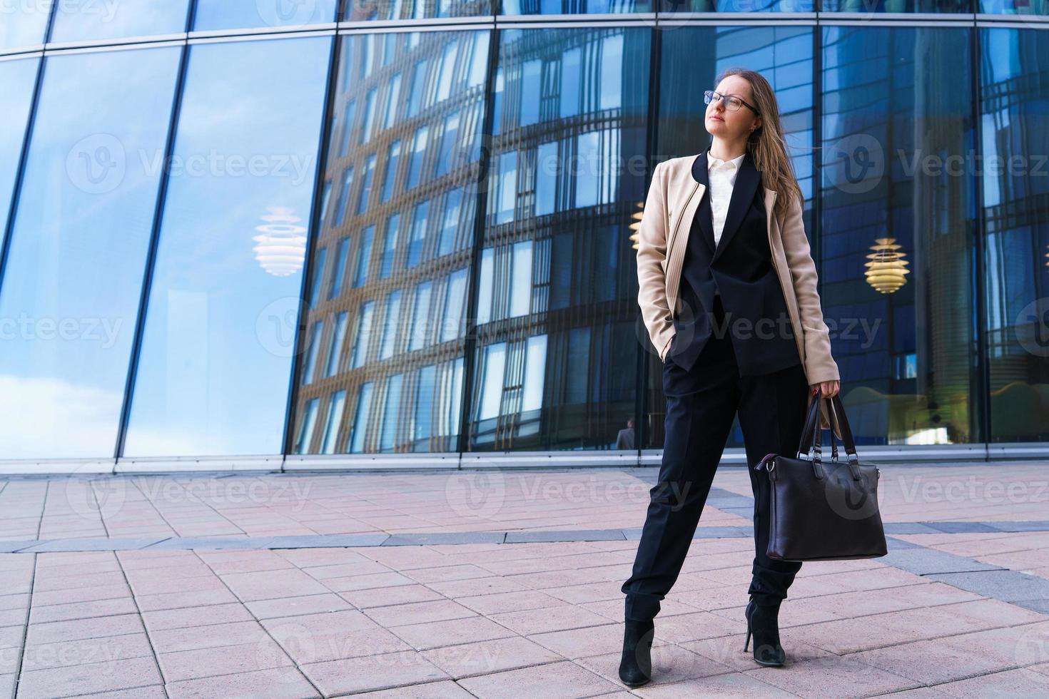 Portrait of a happy successful woman with glasses on the background of an office building photo