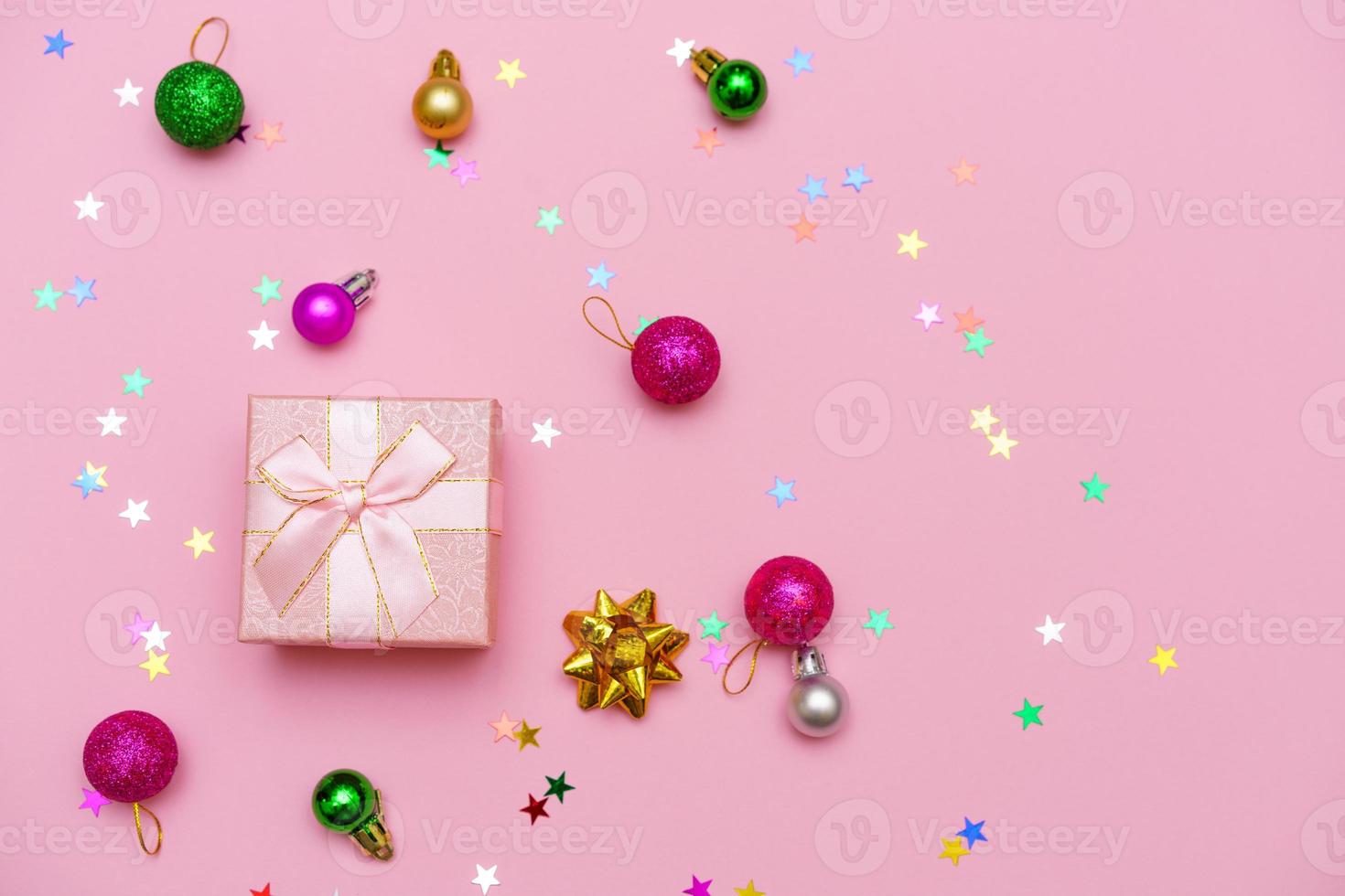 Gift box wrapped with ribbon, decorative balls and snowflake on colorful pink photo