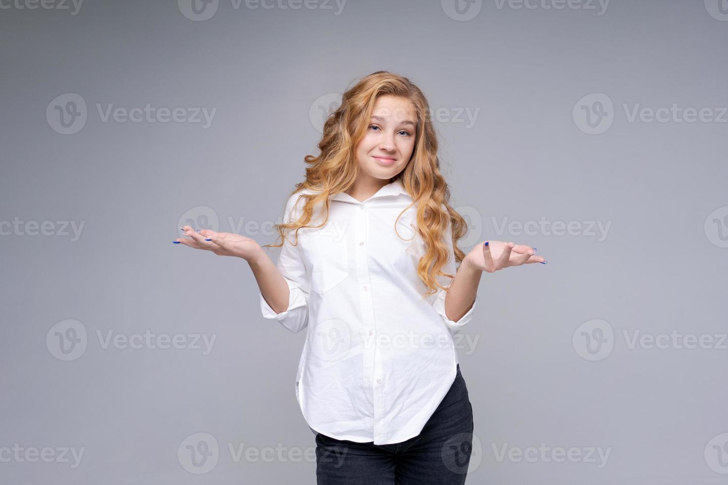 Young caucasian pretty charming blonde woman with wavy hair in white shirt photo
