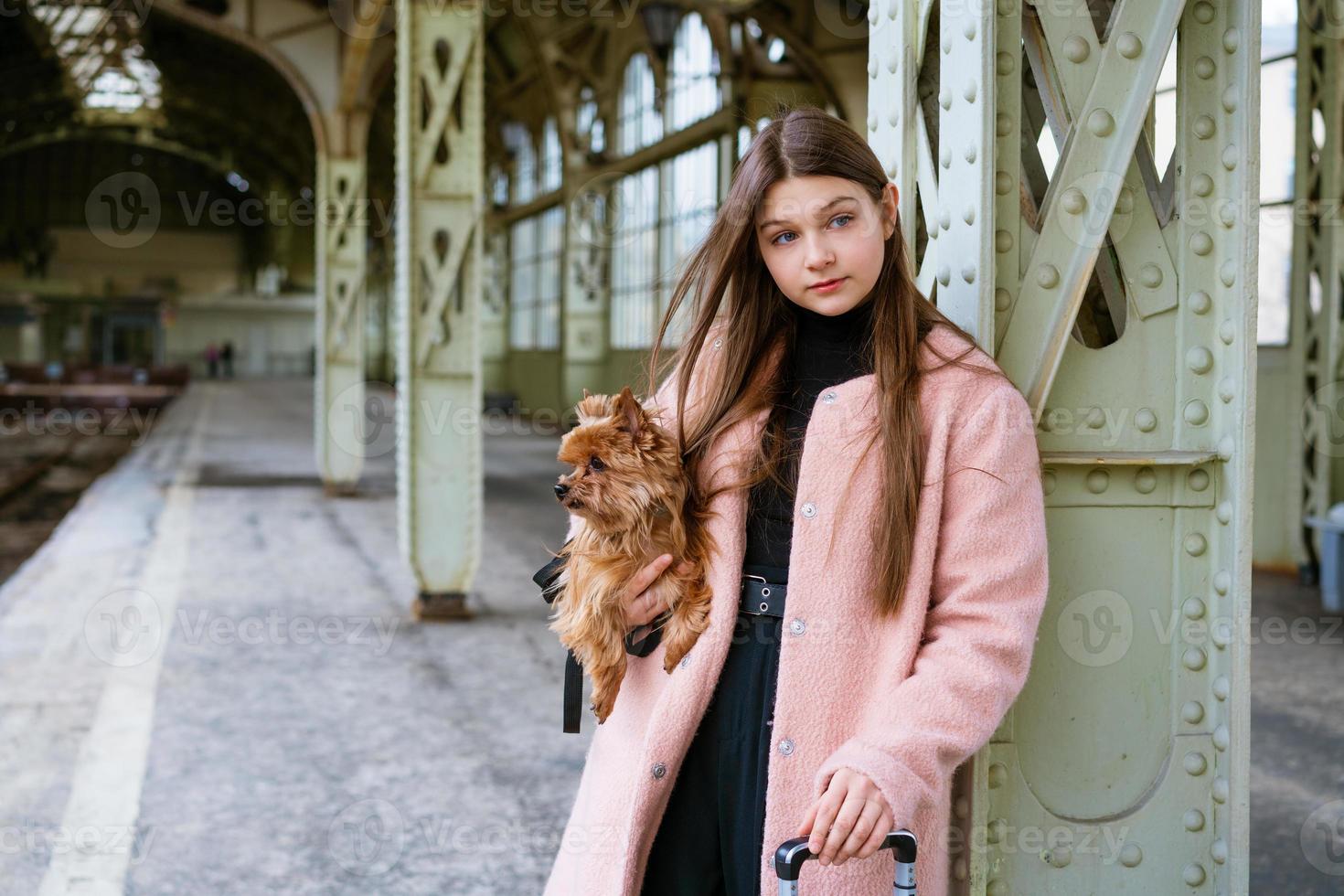 Young girl in pink coat at train station. Beautiful woman stands on platform photo