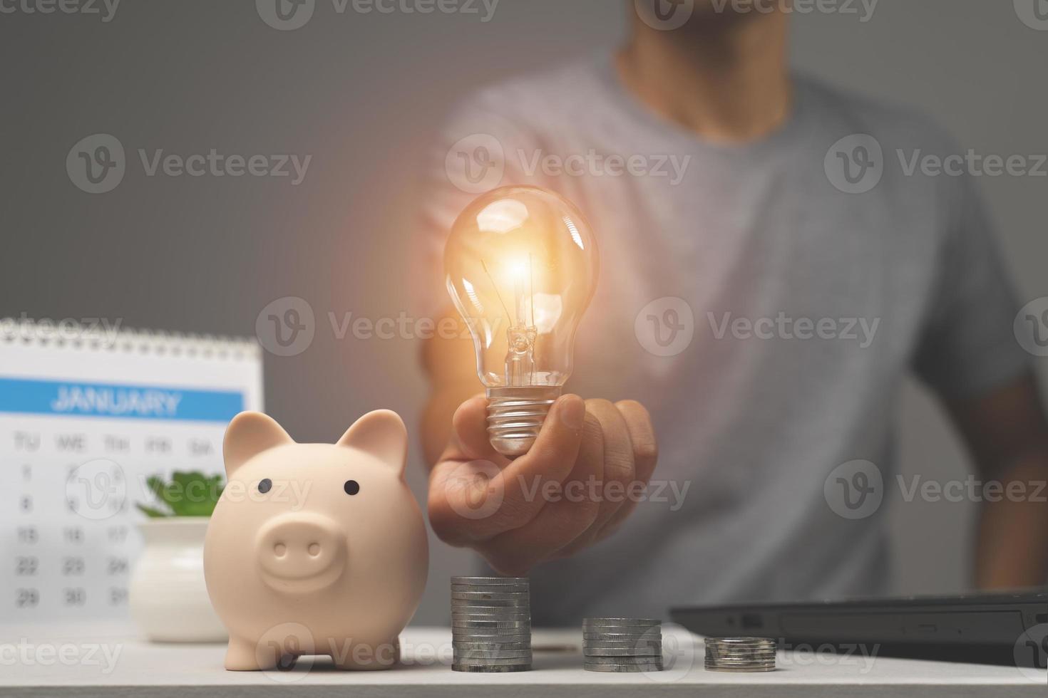 man holding lightbulb on piggy bank and coins stacking on desk. saving money concept photo