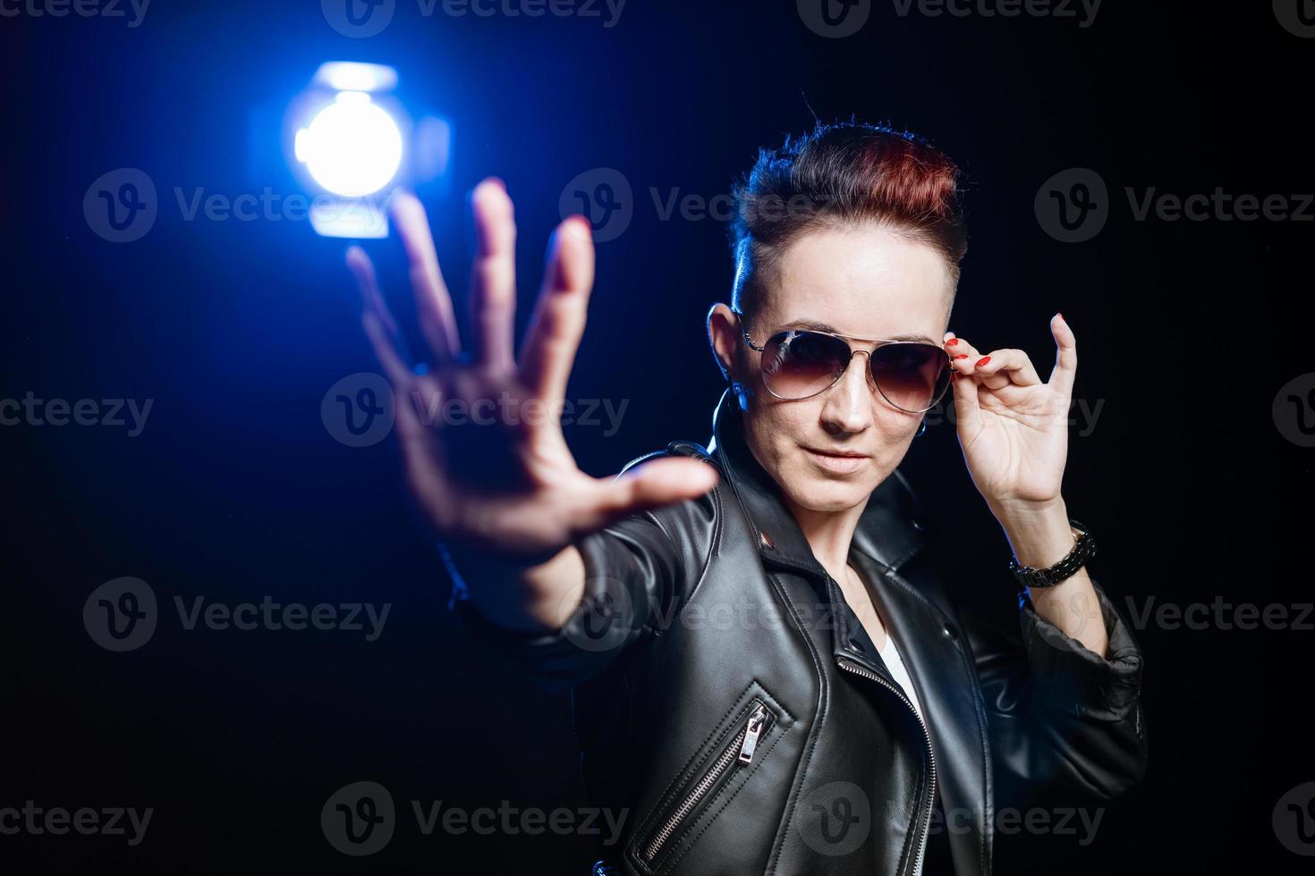 Stylish short haired brunette woman in black leather jacket wearing sunglasses photo