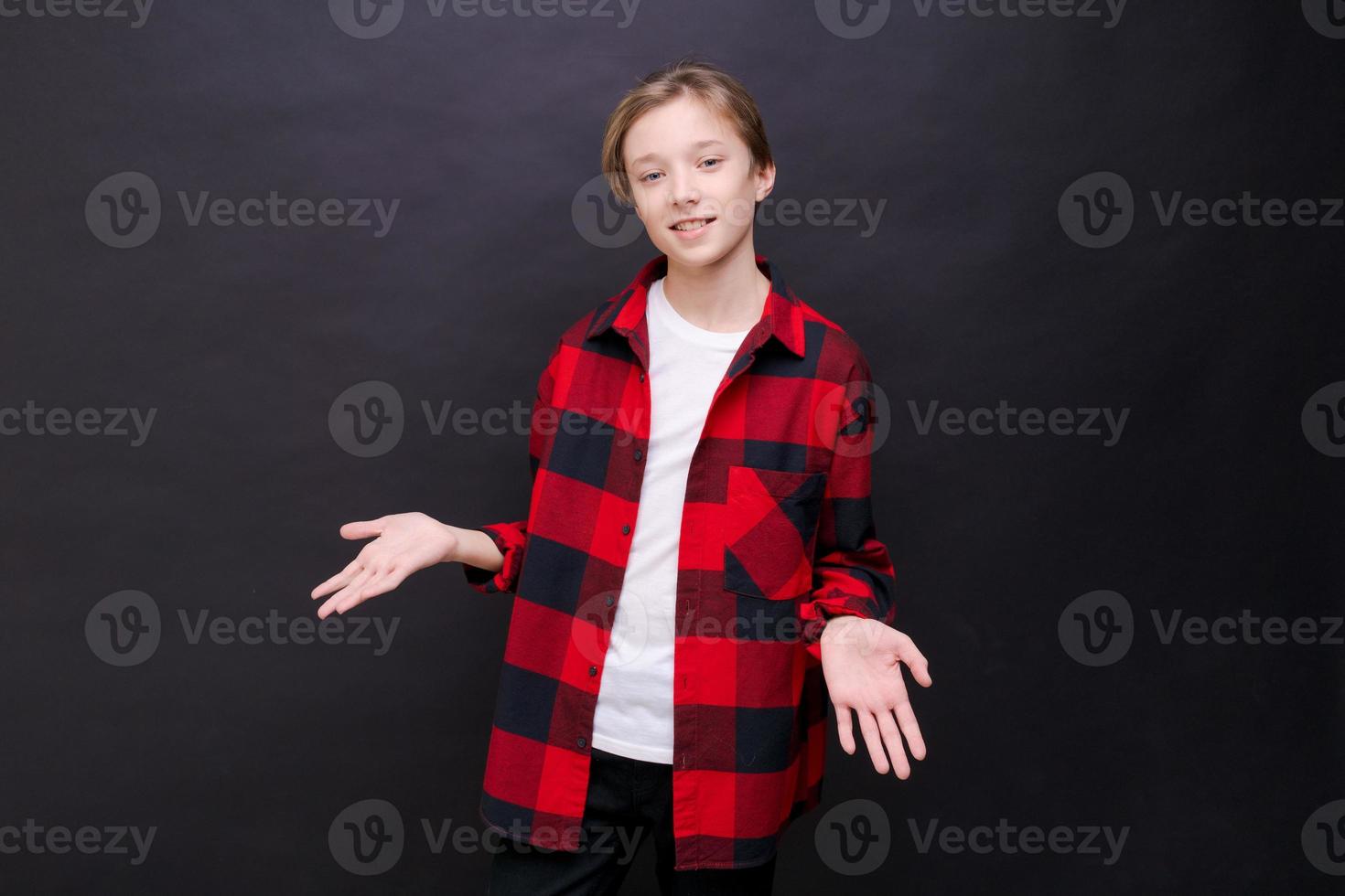 Cute little boy in white t-shirt and red shirt in cage posing on black photo