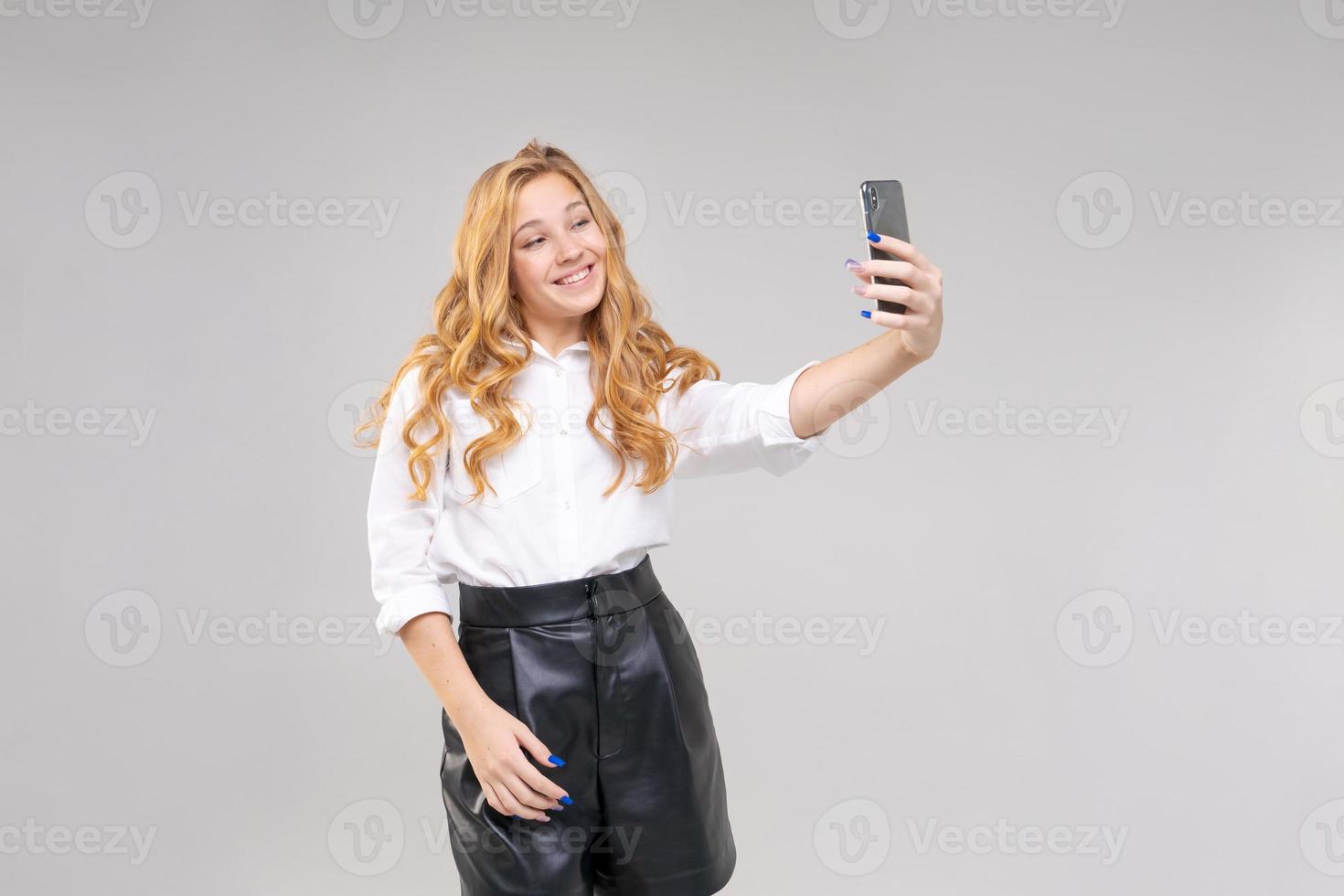Young caucasian girl communicates by video communication using phone photo