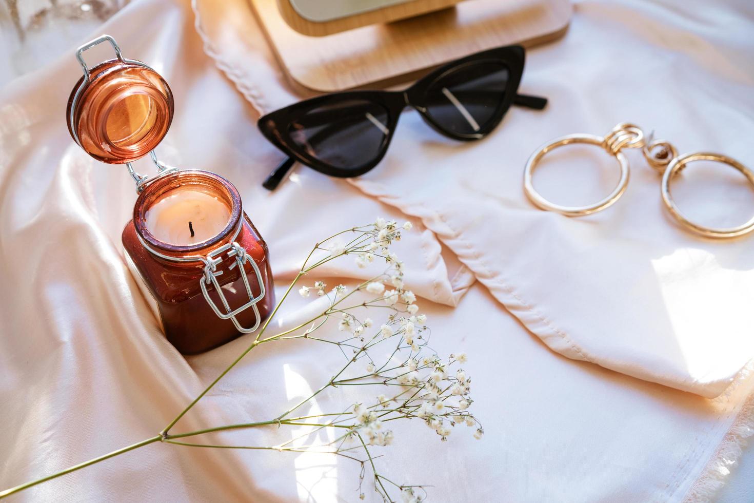 there is a decorative candle in a jar and glasses on the fabric photo