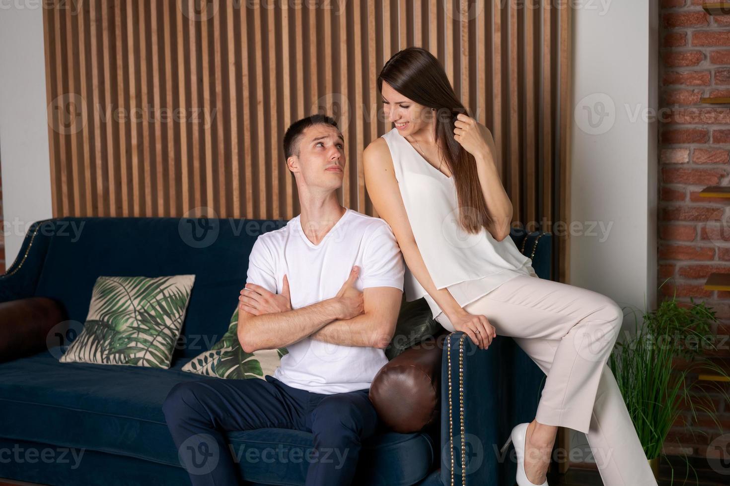 hombre y mujer caucásicos sonrientes abrazándose en el sofá, pasando una intimidad romántica foto