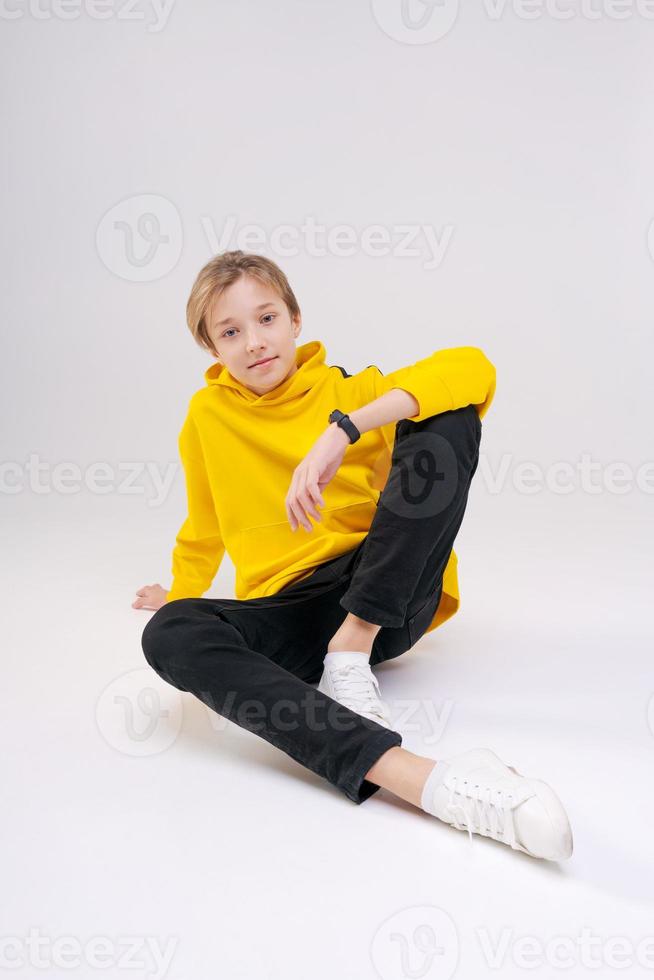 Young handsome happy smiling guy teenager in black jeans, light yellow photo