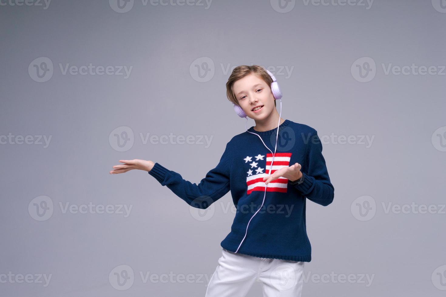 Joyful young man in blue sweater with flag america, stands listening to music photo