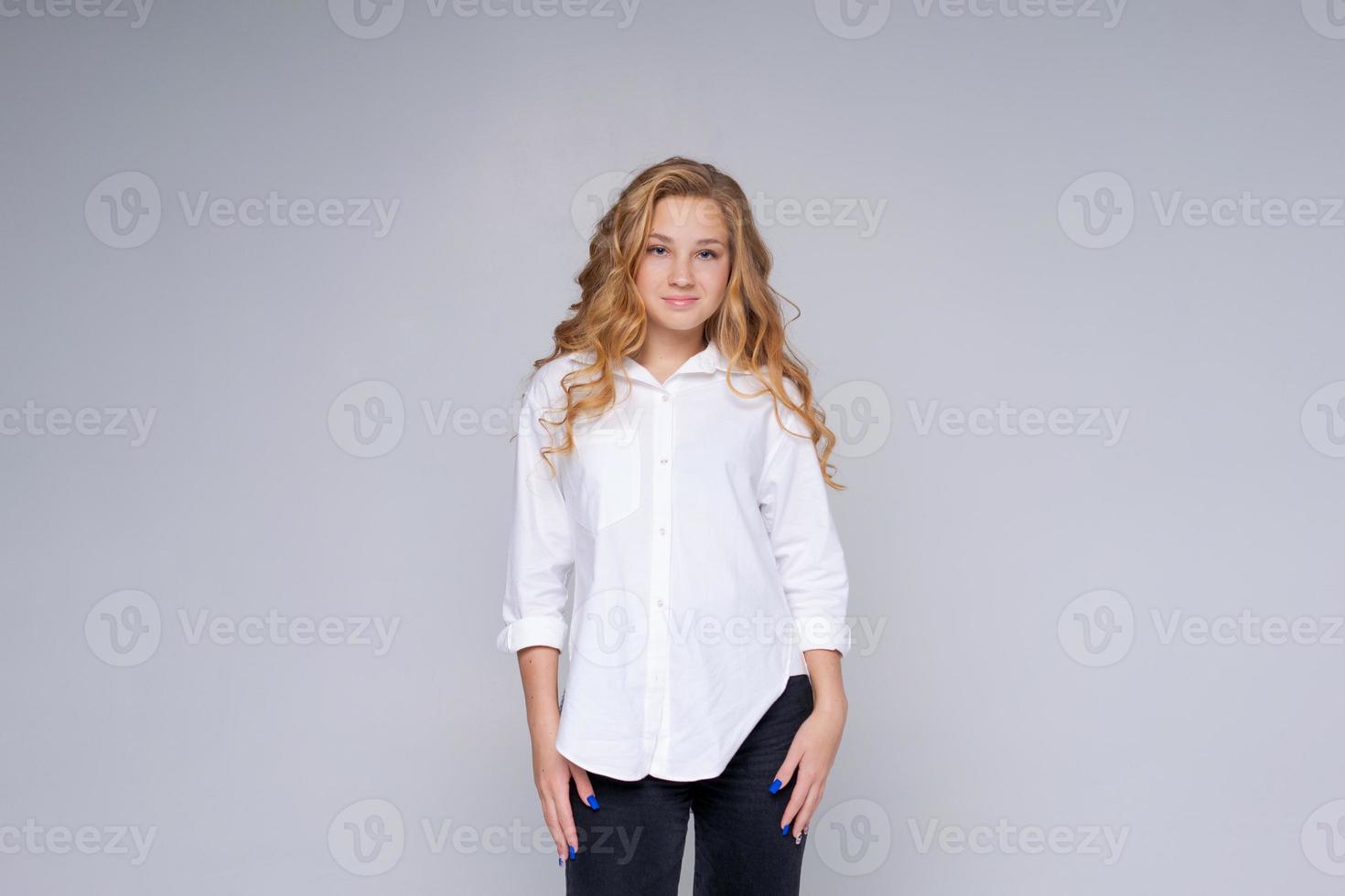 chica caucásica, mujer feliz con cabello largo rubio. en una camisa blanca. maquillaje. foto