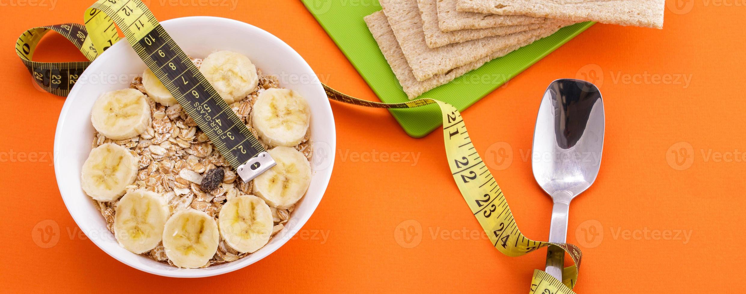 oatmeal  and crispbread lie with spoon and measuring tape on orange background photo