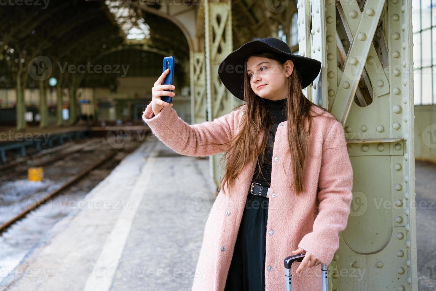Beautiful young woman waiting for train at train station for travel in autumn. photo