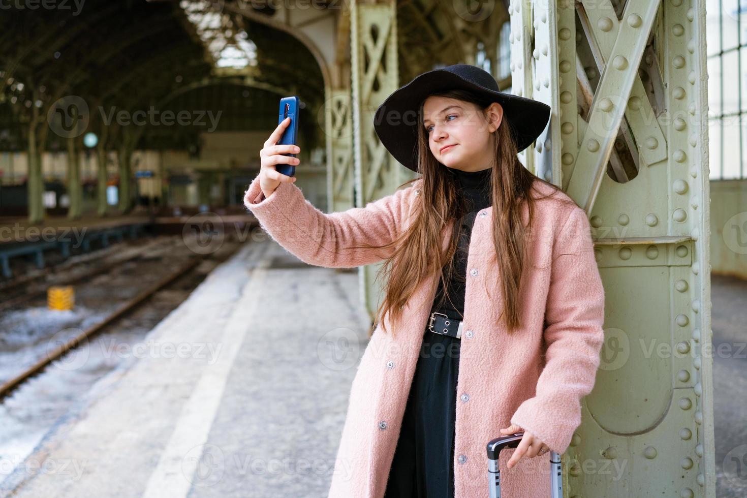 hermosa joven esperando el tren en la estación de tren para viajar en otoño. foto