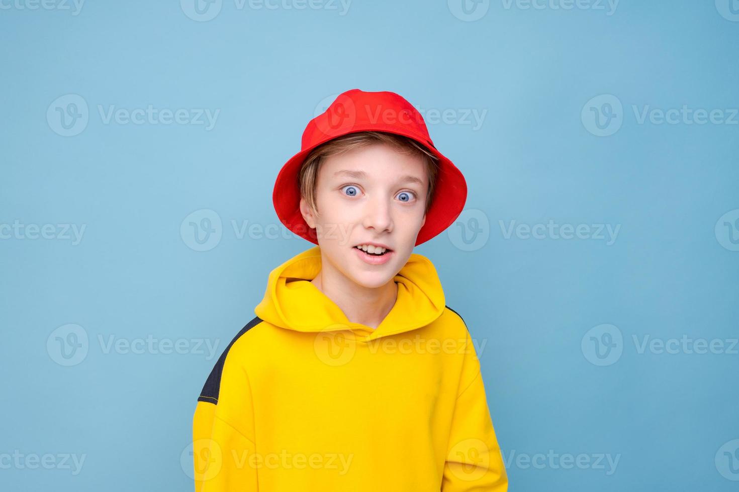 Portrait of a positive guy in a yellow sweater and red panama hat on a blue photo