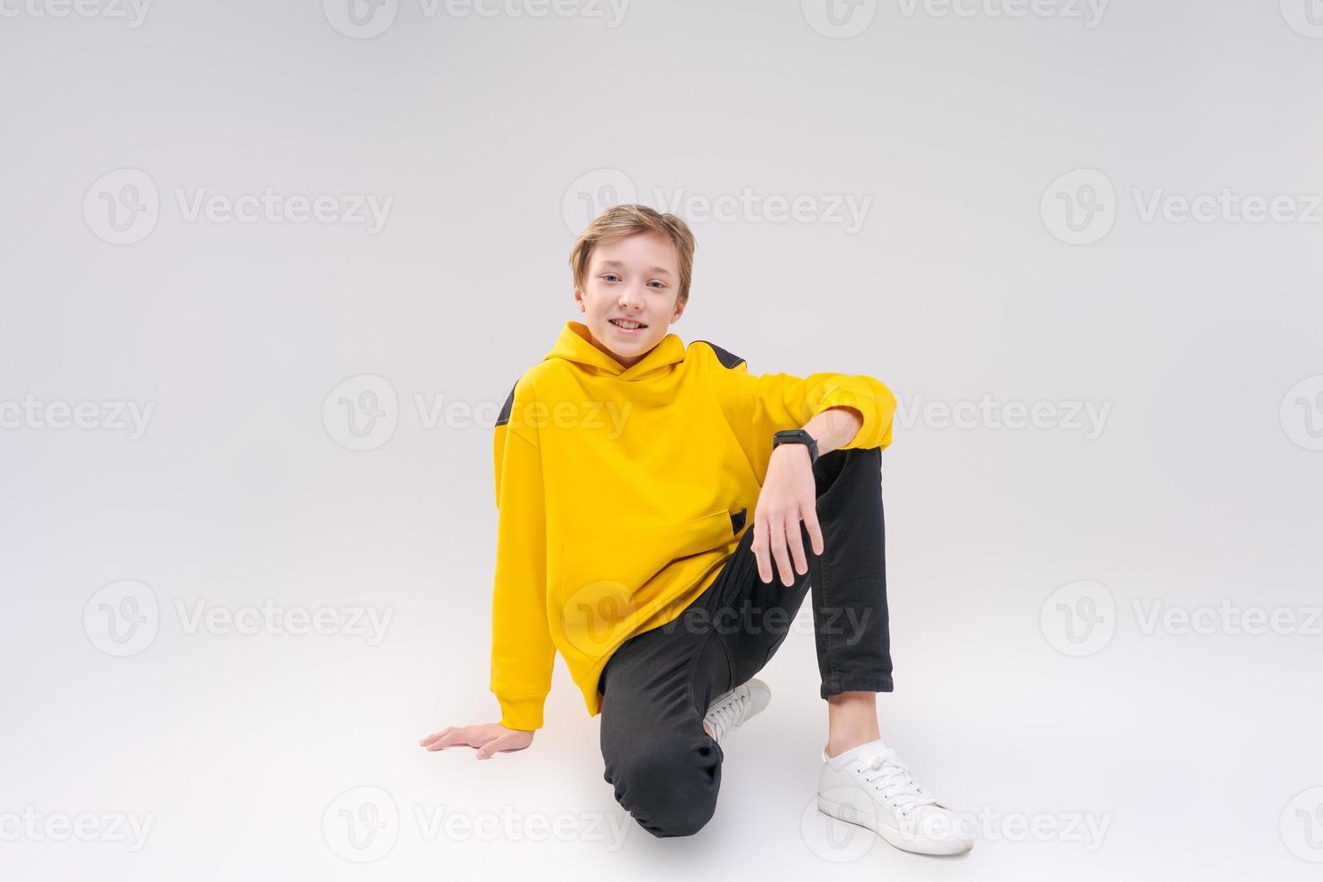 Young handsome happy smiling guy teenager in black jeans, light yellow photo