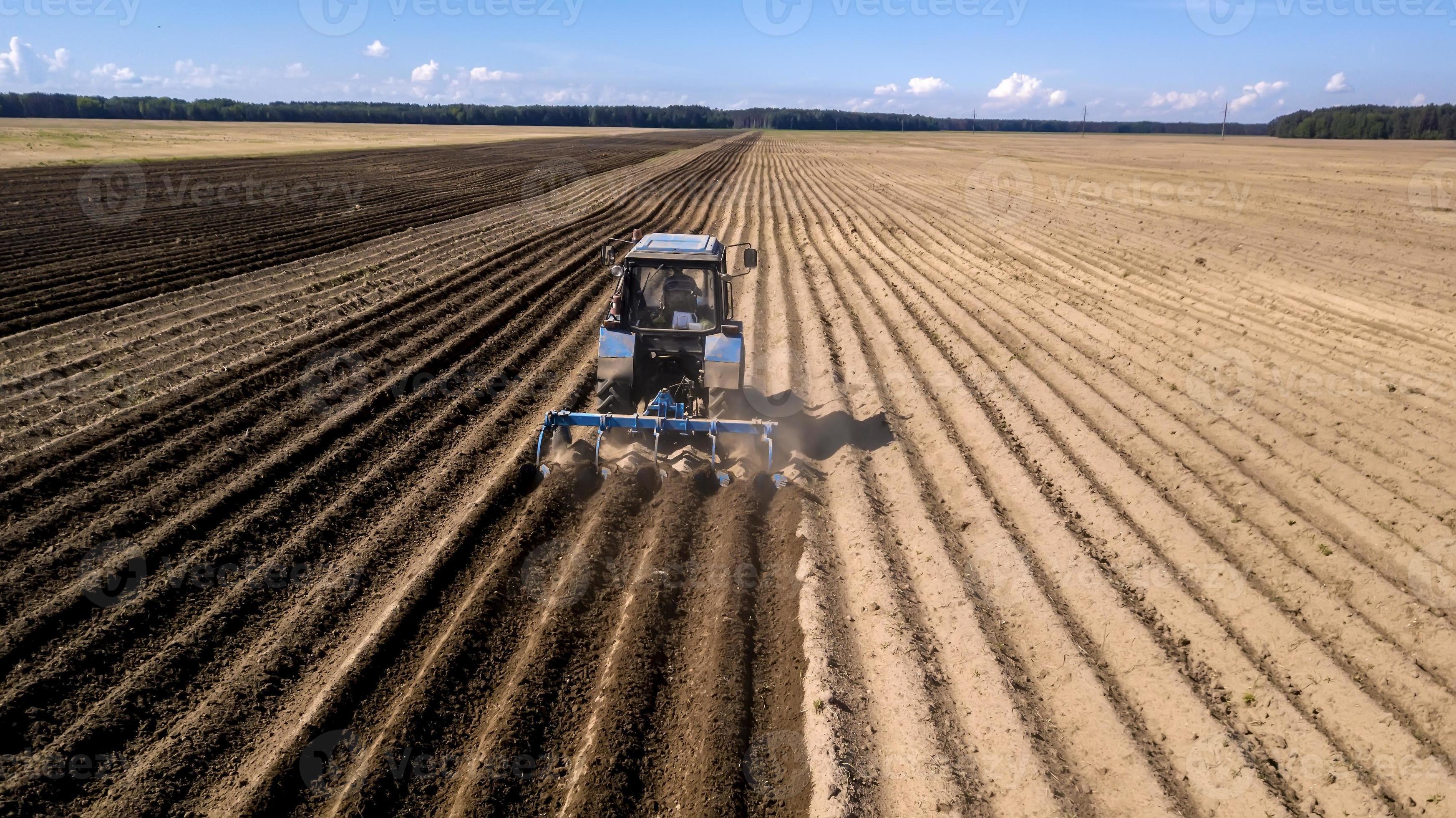 Aerial view to a Tractor with sowing machine working on a field