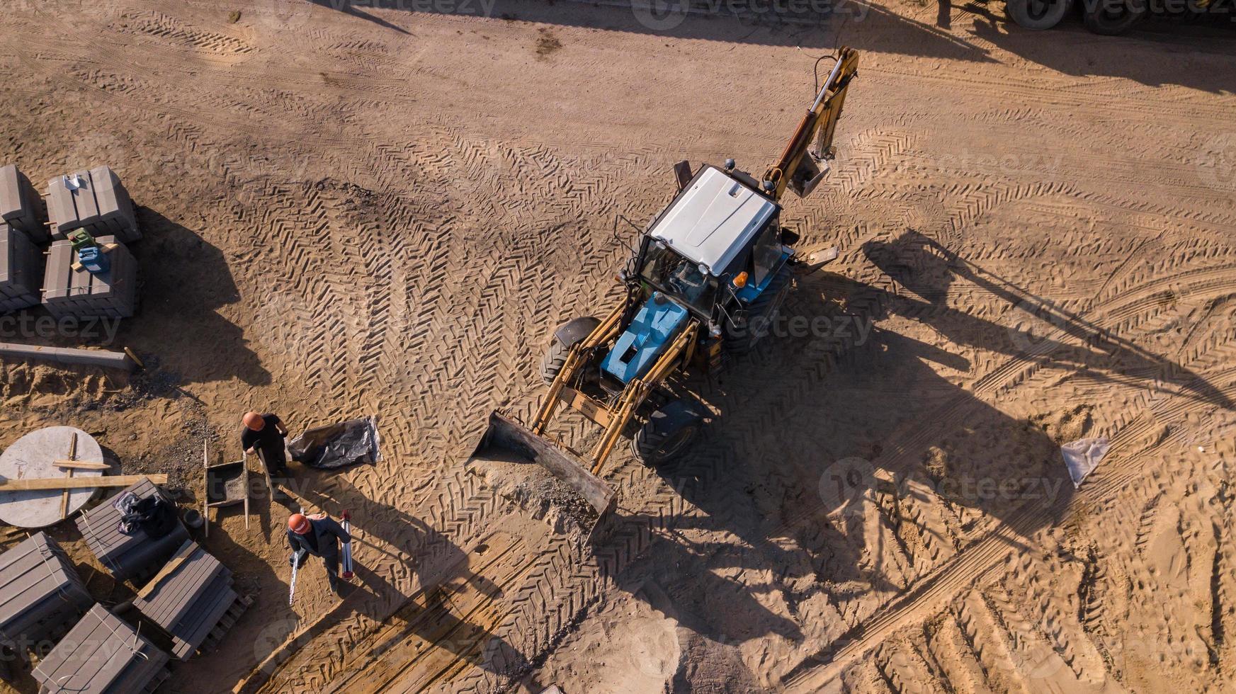 obras de transporte por carretera, reparación, colocación de una gruesa capa de asfalto, hormigón, camiones grandes, tractores, señalización vial, señales de tráfico rojas y amarillas, montones de arena, tierra, edificios antiguos, la gente hace el camino foto