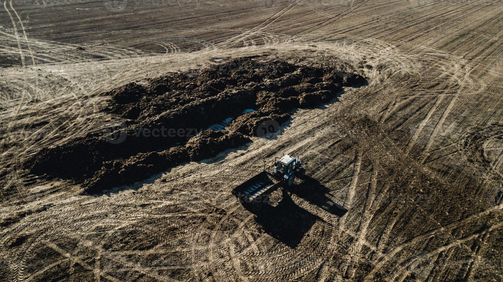 fertilizante en el campo. tractor cerca de la pila de estiércol. encuesta aérea foto