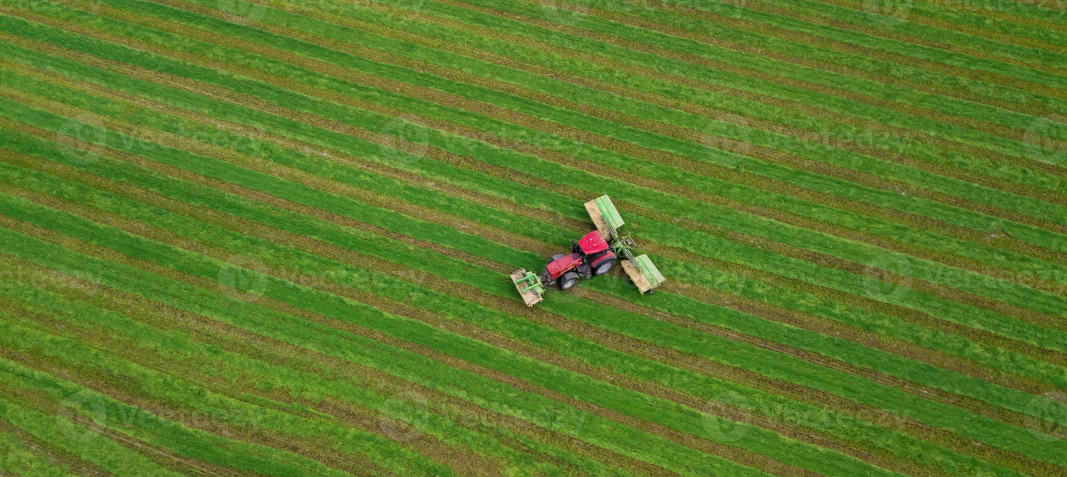 tractor corta la hierba en una vista aérea de campo verde foto