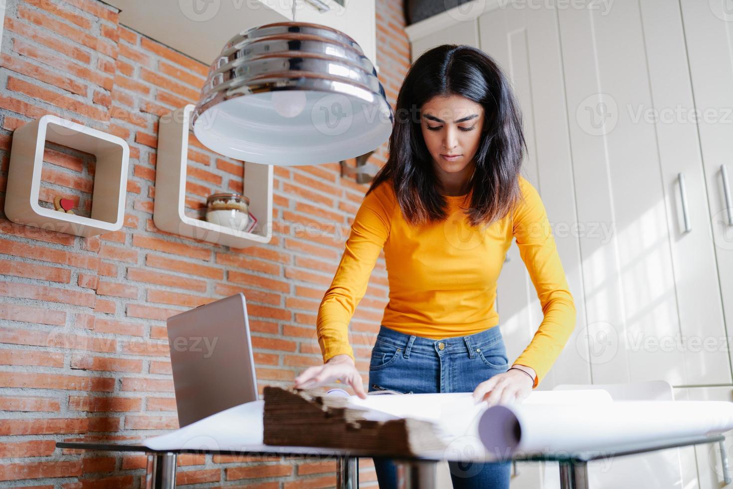 Female architect working at home with a laptop and blueprints photo