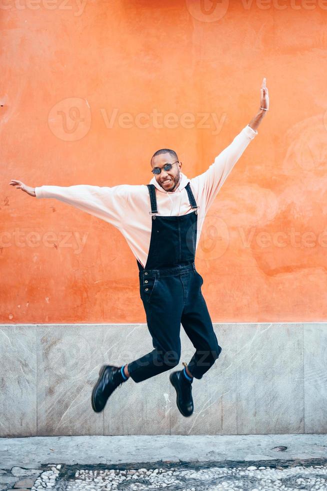 Young black man wearing casual clothes jumping outdoors photo