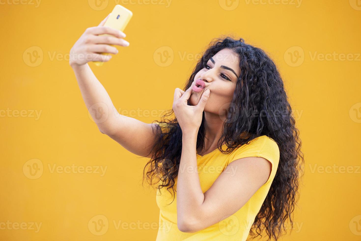 Young Arab woman taking selfie photograph with smartphone. photo