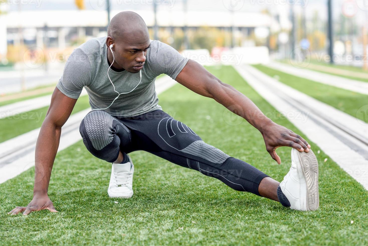 Black man doing stretching before running in urban background photo