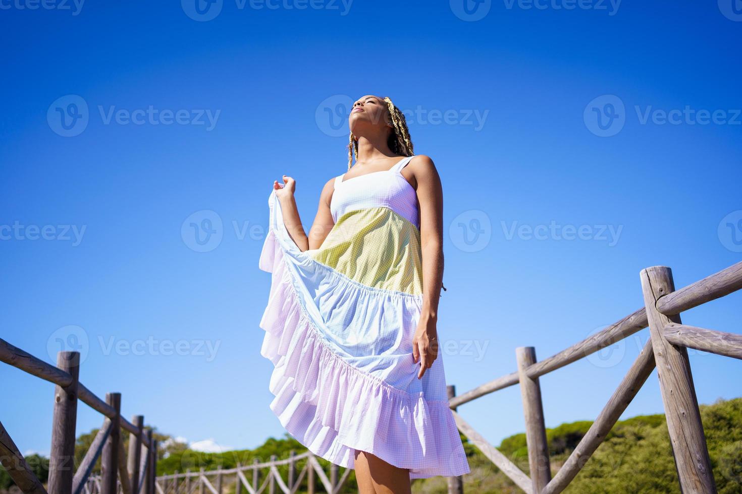 African woman wearing a beautiful dress on a boardwalk on the beach. photo