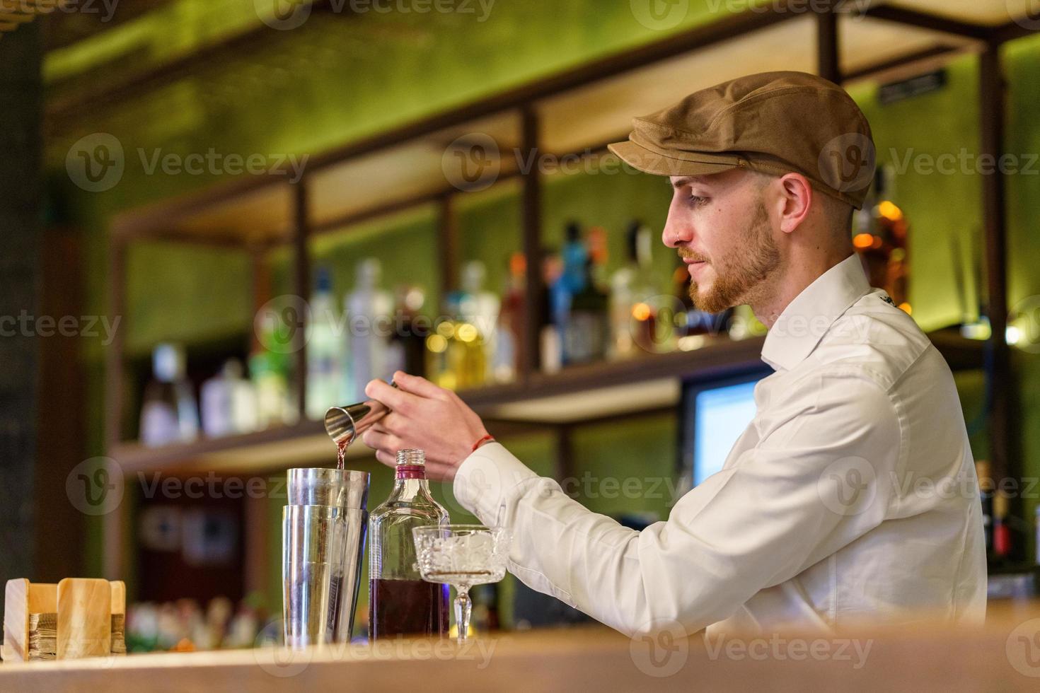 barman masculino vertiendo alcohol en la coctelera foto