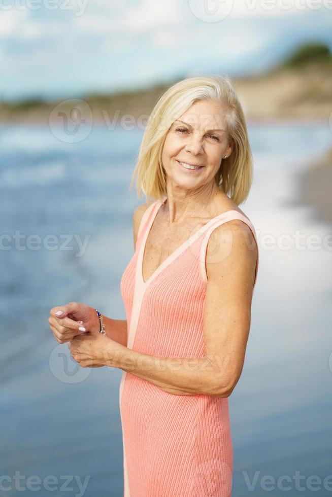 Mature woman on shore of a beach. Elderly female enjoying her retirement at a seaside retreat. photo