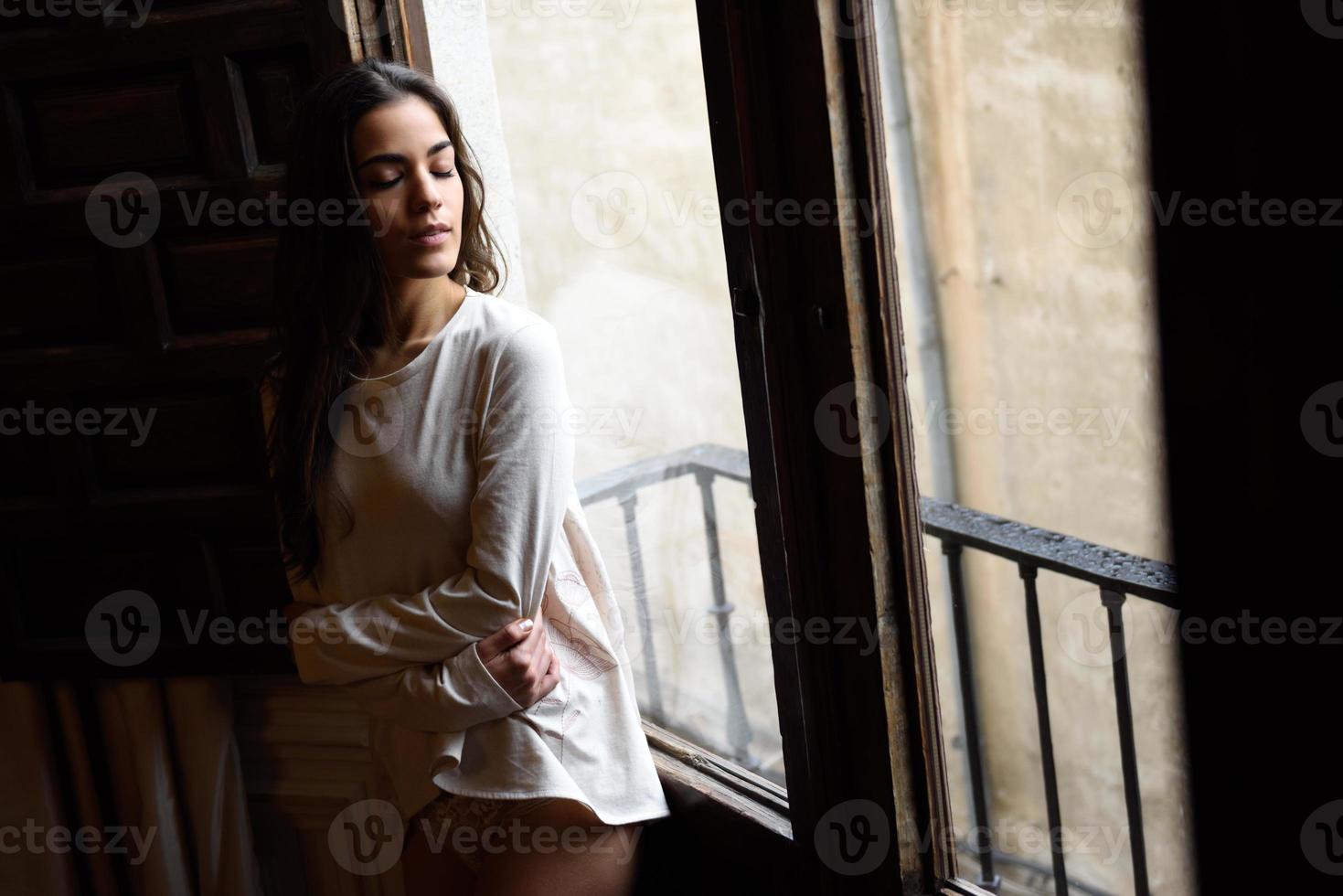 mujer en pijama y bragas blancas posando cerca de una ventana foto