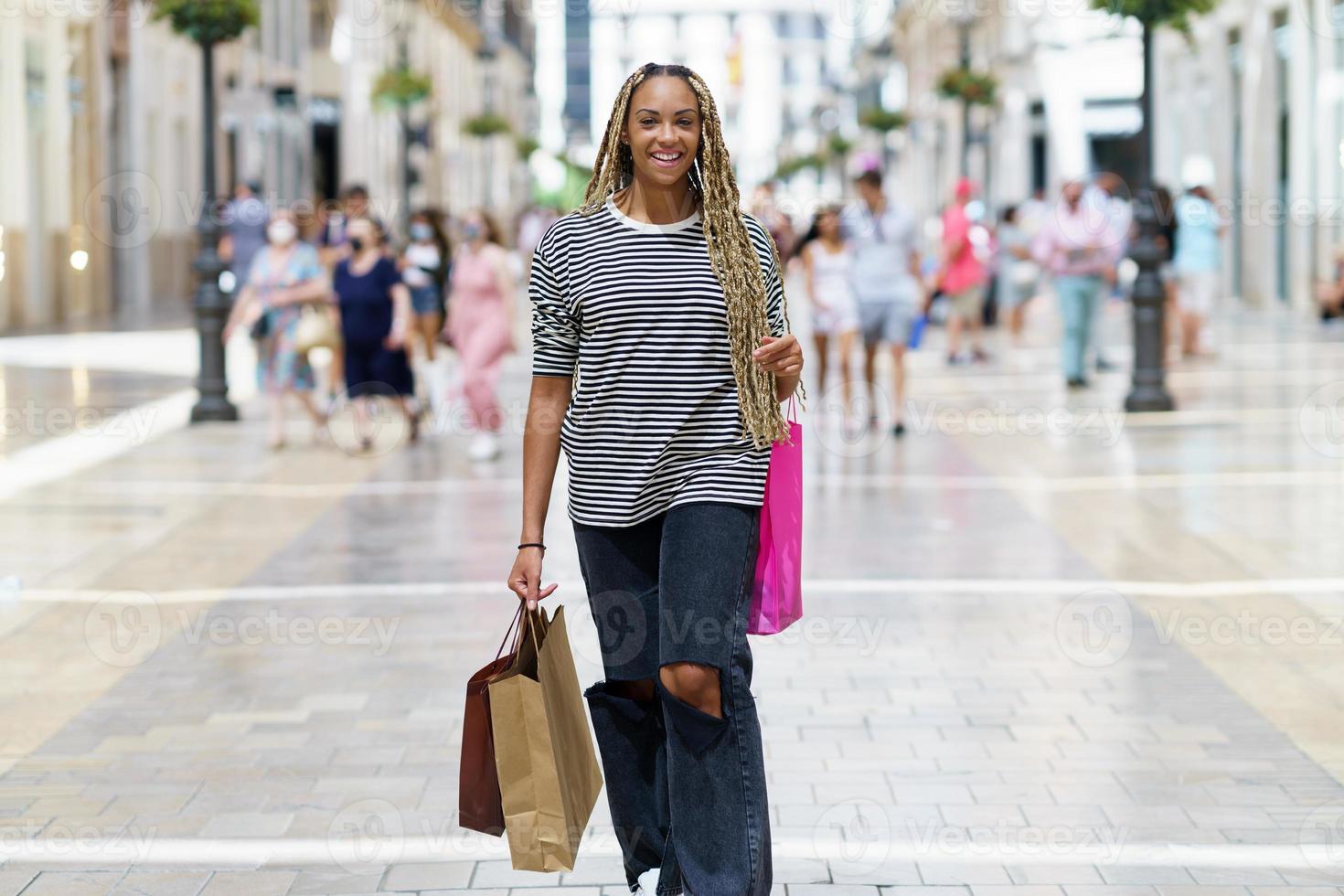 Black female, with coloured braids, with shopping bags in the street. photo
