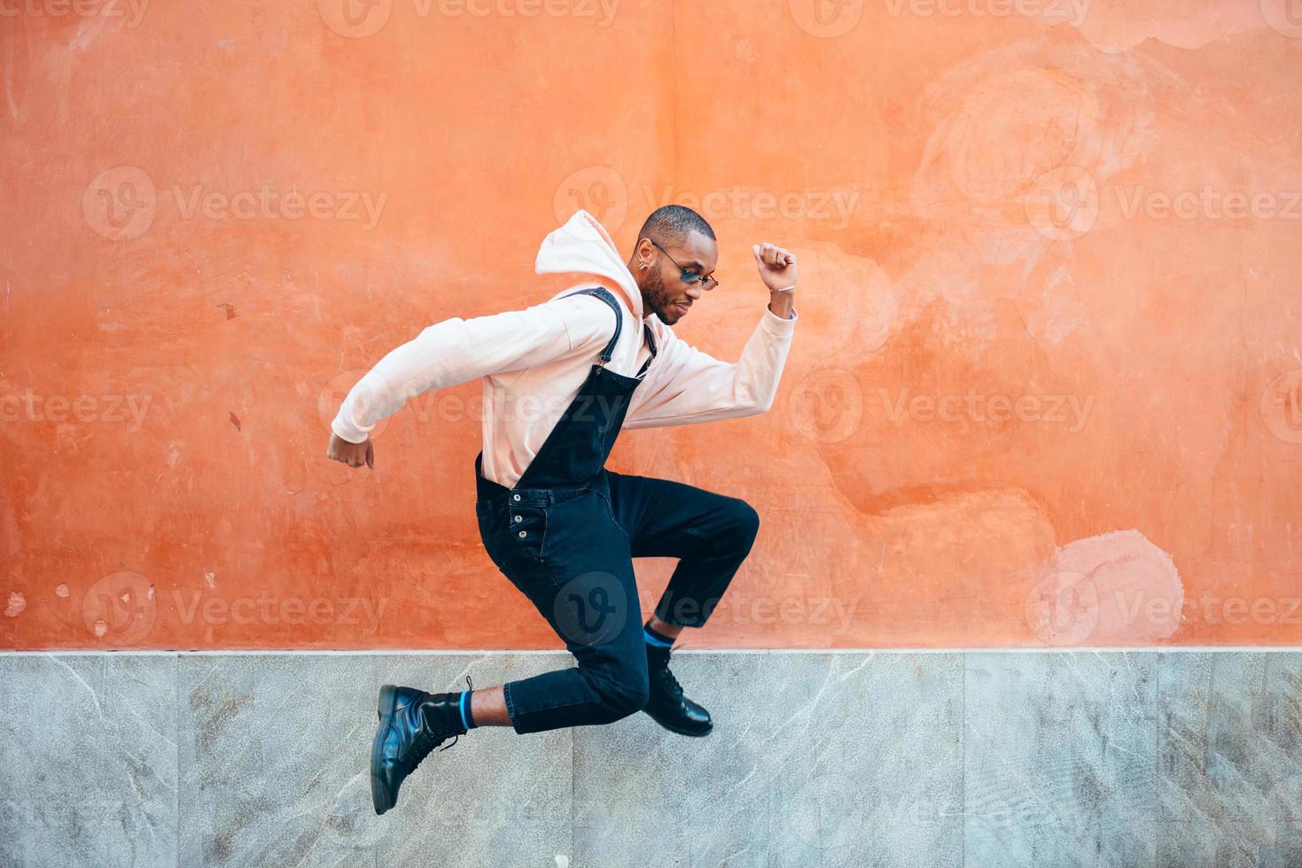 joven negro con ropa informal saltando al aire libre foto