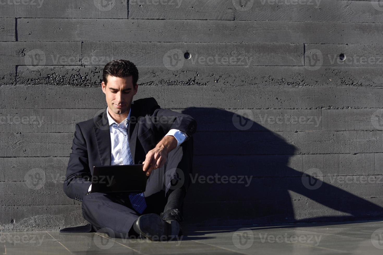 Businessman using a laptop computer sitting in the street photo